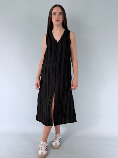 Abito midi nero con scollo a V senza maniche. Modello svasato con spacco sul davanti.