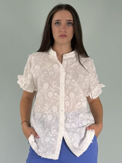 camicia ricamata con manica corta e volant. Allacciata sul davanti con bottoni.