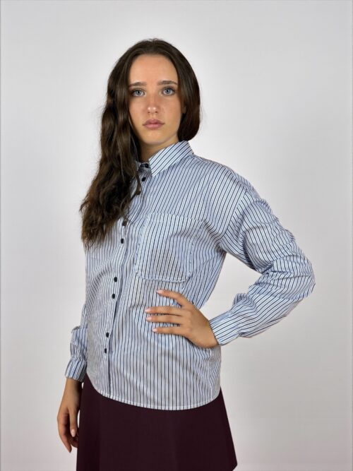 Camicia a righe, manica lunga con colletto. Dettaglio del taschino, allacciata sul davanti con bottoni a contrasto.