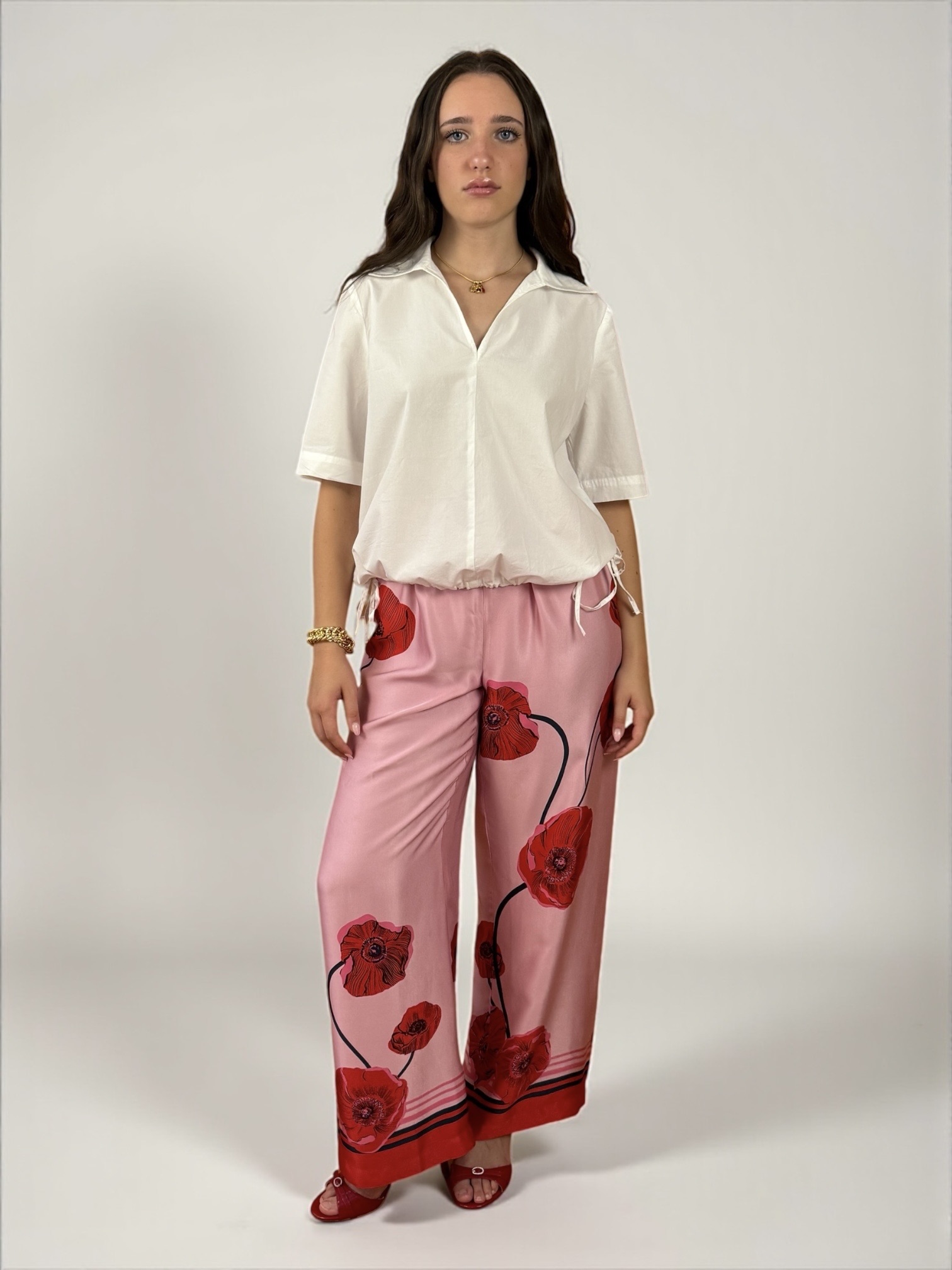 Blusa a maniche corte con scollatura a V e colletto. Presenta due spacchetti laterali e due laccietti che creano un effetto arricciato.