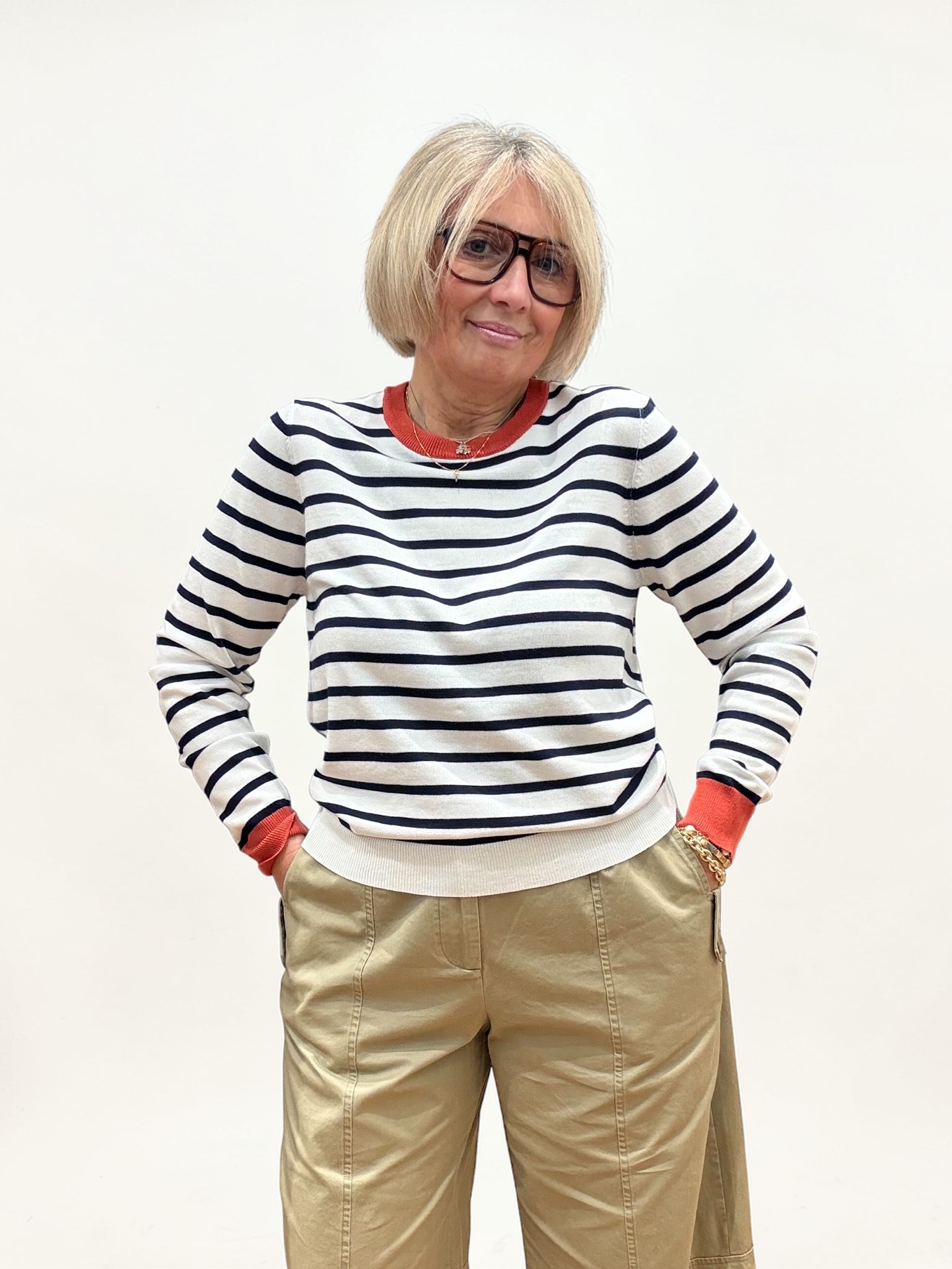 Maglia in filo a righe bianca e blu. Girocollo e polsini di colore coccio. Ideale da indossare con capi casual.