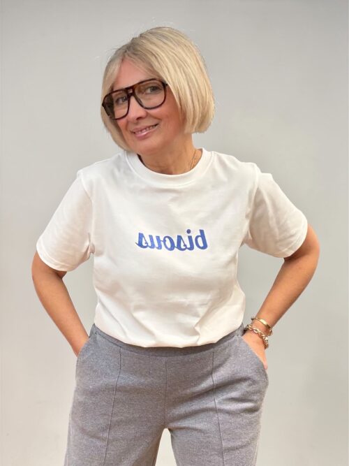 T-Shirt bianca con scritta bluette glitterata. Modello a girocollo e maniche corte dritto. Ideale da abbinare sia con jeans, pantaloni o gonne.